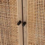 Close-up of black cylindrical door pull hardware on woven cane panel doors
