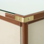 Close-up of dresser corner showing glass top, leather-wrapped frame, and brass corner bracket
