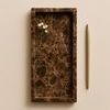 Brown Emperador Tank Tray shown vertically on beige surface with a gold pen and small white flowers