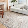 Rug styled in living room with white sofa, wooden chair, and plant on light wood floor