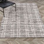 Rug displayed flat on chevron wood floor with modern black chair leg visible
