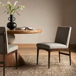 Abida Alcala Nickel Dining Chair shown in a dining room setting with wood table and decorative vase