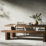 Styled dining scene with woven chairs, beige wall, and sunlight casting shadows