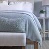 Rectangular Murphy Pillow styled at foot of bed in bedroom with light blue bedding and wooden furniture