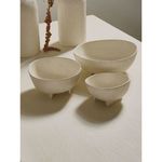 Set of three off-white aluminium bowls styled on table with decorative vases in natural light