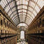 Close-up of glass roof structure and ornate wall sculptures printed on glossy metal surface