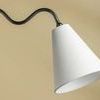 Close-up focusing on single white linen shade suspended from black squiggly arm