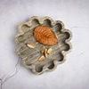 Brown marble tray styled with dried leaf and petals on cracked light gray surface