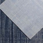 Overhead crop showing light blue rug placed over patterned dark blue area rug