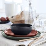 Pacifica bowl empty, placed on terracotta and green plates, styled with glassware and bread in the background