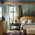 Wider bedroom shot showing exposed ceiling beams, patterned wall, and floor rug beside the bed
