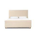 Partial side view of Dalia Bed footboard showing linen fabric and wooden turned foot