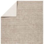 Corner of rug flipped over highlighting cream backside and construction detail