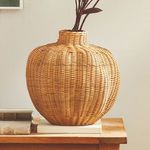 Warm natural rattan color Evren Vase styled on wooden surface with decorative branches inside