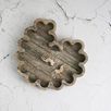 Tray styled on a cracked white surface holding a pair of gold sunburst earrings