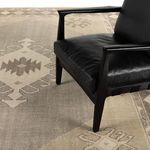 Samsa rug under black leather chair displaying rug pattern scale and room placement