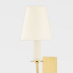 Iantha 1 Light Wall Sconce with brass finish, curved arm, rectangular wall plate, and cream fabric shade