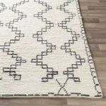 Close-up angled view showing plush texture and edge detail of Beni Ourain wool rug on wooden floor