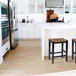 Haven stool placed in modern kitchen setting with white island, wooden flooring, and stainless steel appliances