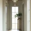 Falls Pedestal Table placed in a bright hallway near a window with a vase of greenery on top