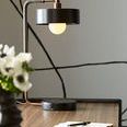 Close-up of lamp on desk partially lit with blurred flowers and notebook in foreground
