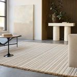 Rug in modern living room with concrete floor, side table, vase, and wood slat wall