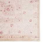 close-up of rug corner highlighting soft floral pattern in pink on white background