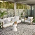 Styled outdoor patio setting featuring the ivory patterned rug under modern seating with plants and stone wall