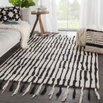 Saville rug styled in living room with sofa, pouf, side table, and window light