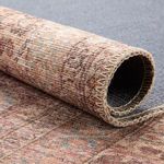Edge of rug rolled showing pile texture and stitched binding in beige thread