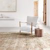 Theia Taupe Gold Rug in a modern bright room with armchair and side table, showing scale and overall style