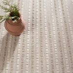 close-up on textured rug surface with decorative terra cotta vase casting shadow