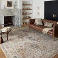 Rug styled in living room with brown leather sofa, fireplace, and decorative shelves