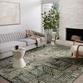 Rug in a bright living room setting with a light gray sofa, fireplace, and wood accent chair