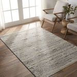 Duna rug styled in bright room with wooden floor and white cushioned chairs