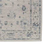 Close-up of rug border showing detailed distressed floral motifs in blues and grays