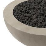 Close-up of smooth concrete rim and textured black lava stones inside fire table bowl