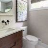 Framed rain drops art hanging on light gray bathroom wall above white toilet and dark wood vanity