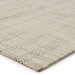 Close-up corner view showing wool texture and handwoven details of the cream and black striped rug