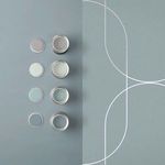 Close-up of paint cans arranged beside wallpaper showing complementary color palette
