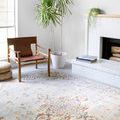 Vintage style rug styled in living room with wooden chair, potted plant, and white fireplace
