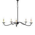 Saxon chandelier over round wood dining table with four beige upholstered chairs in natural light from window