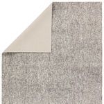 Back side of the rug with one corner folded over revealing smooth solid cream backing