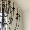 Close-up of upper section of Erika chandelier showing beige candle sleeves with clear bulbs and curved iron arms