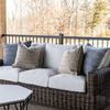 Montauk sofa decorated with blue and beige patterned pillows on a wood porch with black metal railing