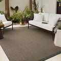 Providence rug styled outdoors beneath white cushioned seating with plants and patio surroundings