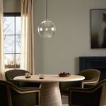Clear glass globe pendant lighting modern dining table with dark green chairs and natural light