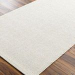 Close-up angled view showing the fine, tight weave and light beige color of the Birdie rug