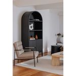 Verlaine chair styled in modern living space with black bookshelf, beige rug, and wood floor
