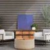 Two Hearst Outdoor Chairs placed on wooden deck with dark gray siding, natural wood cabinet, and plants